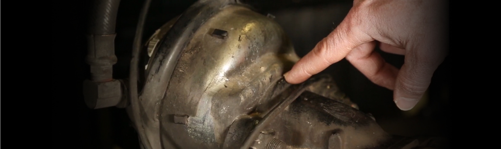 Technician pointing to where the brake chamber mounts to the caliper on a heavy-duty air disc brake
