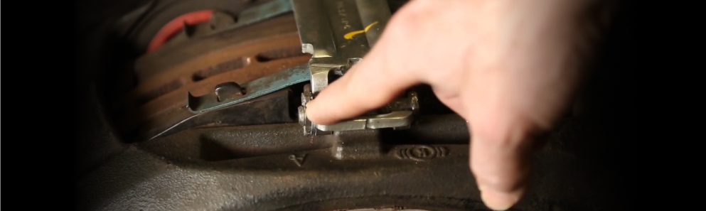 Technician checking the brake pad retainer and retention hardware on a heavy-duty air disc brake