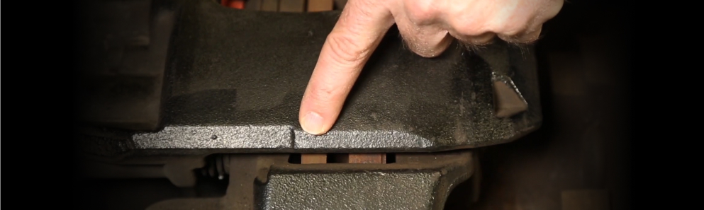 Technician pointing to the cast-in brake pad wear indicators on a heavy-duty air disc brake caliper