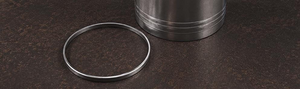 Close-up of a heavy-duty anti-polishing ring next to a cylinder sleeve