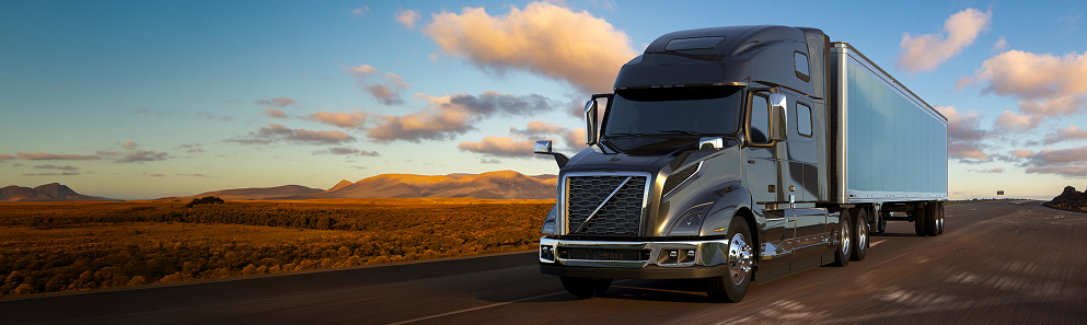 Heavy-duty semi truck traveling on a desert highway at sunset