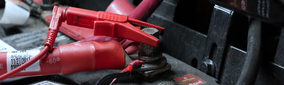 Positive red charging cable attached to a car battery terminal
