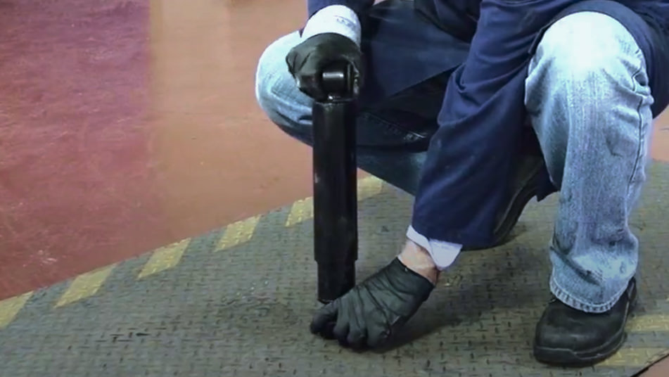 auto technician checking shock travel by hand