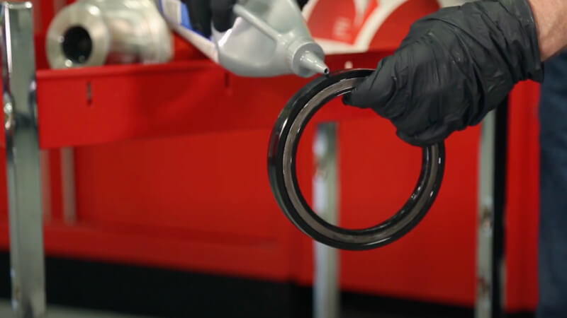 man applying oil to wheel end seal