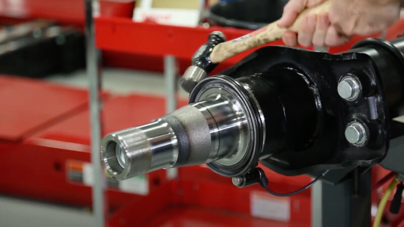 man removing spindle mounted seal striking with hammer