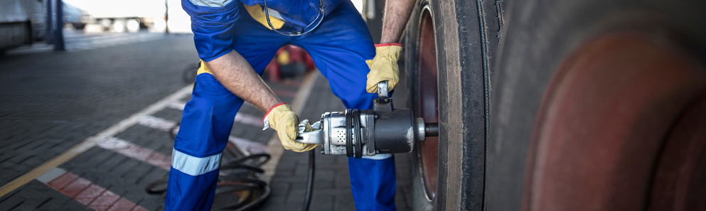technician using impact wrench on heavy-duty wheel